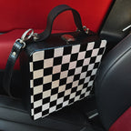 Black and white checkered wooden handbag with leather strap on car seat, handmade artistic accessory.